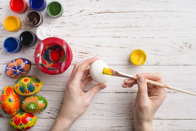 Top view of hands painting an egg for easter day