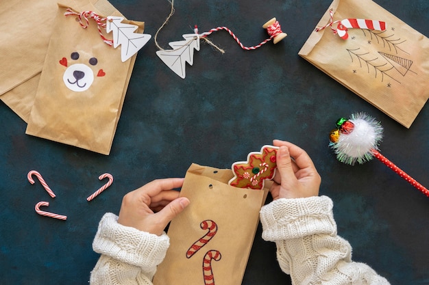 Top view of hands putting treats inside christmas gift bags