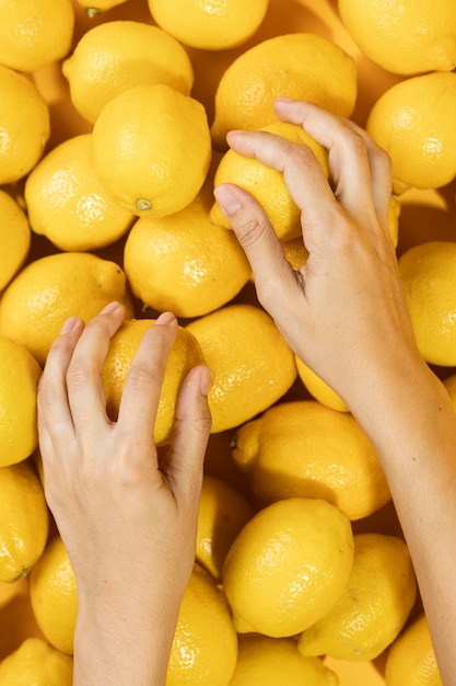 Free photo top view hands touching fresh lemons