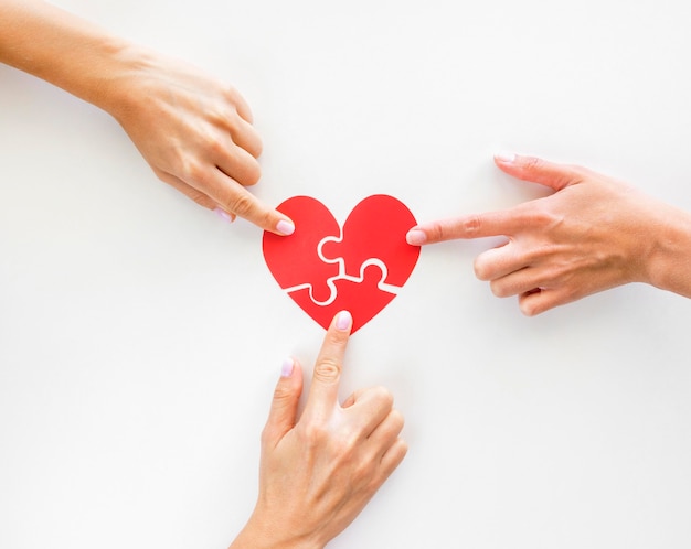 Top view of hands touching puzzle heart pieces