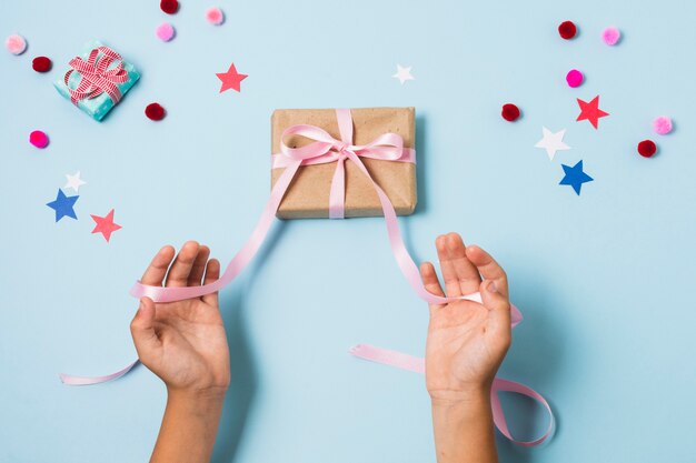 Top view of hands tying present with ribbon