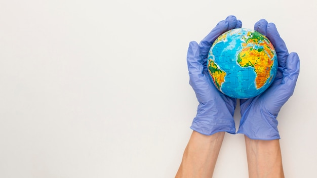 Top view of hands with gloves holding earth globe