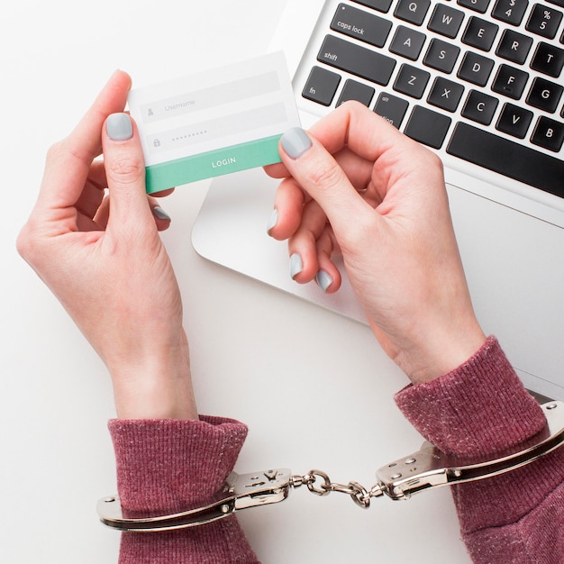 Free photo top view of hands with handcuffs holding username and password information