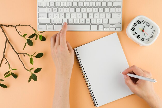 Top view of hands with notebook on desk and keyboard