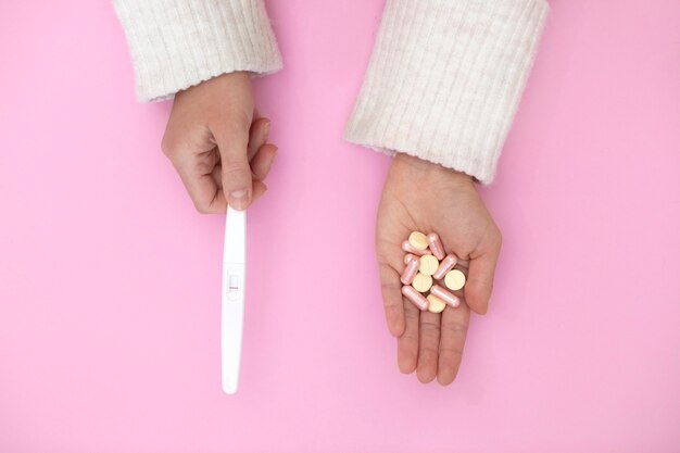 Top view hands with pregnancy test and pills