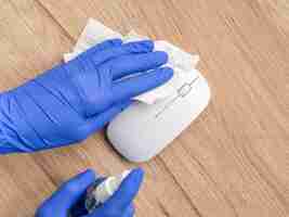 Free photo top view of hands with surgical gloves disinfecting mouse with napkin