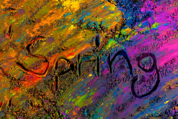Top view of handwritten spring text on multicolored holi powder