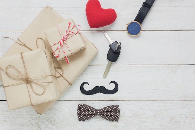 Top view Happy Father day.accessories with red heart,mustache,vintage bow tie,present,key's car on rustic white wooden background.