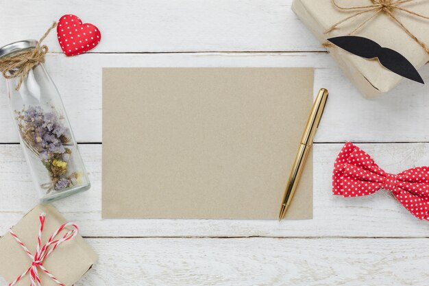 Top view Happy Father day.Blank space paper for free text  on rustic wooden background.accessories with ,red heart,gift,mustache,vintage bow tie,dried flower in the bottle and present.