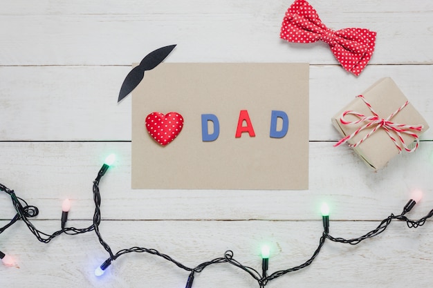 종이, 조명, 선물, 콧수염, 빈티지 나비 넥타이 존재와 나무 소박한 나무 background.accessories에 상위 뷰 해피 아버지의 날. 붉은 마음과 단어 "DAD".