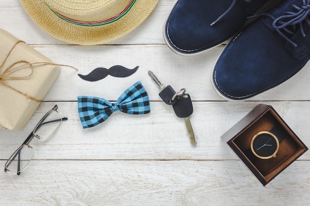 Top view Happy Father day on rustic wooden background. accessories with watch,mustache,vintage bow tie,pen,present,key car,shoes and hat.