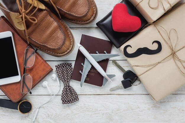 Top view Happy Father day with travel concept. Airplane and passport on rustic wooden background. accessories with red heart,mustache,vintage bow tie,pen,present,white mobile phone,shoes ,earphone,watch and notebook.