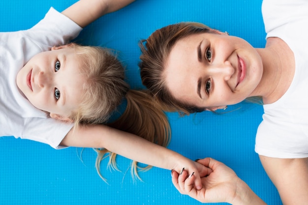 Top view of happy mother posing with daughter on yoga mat