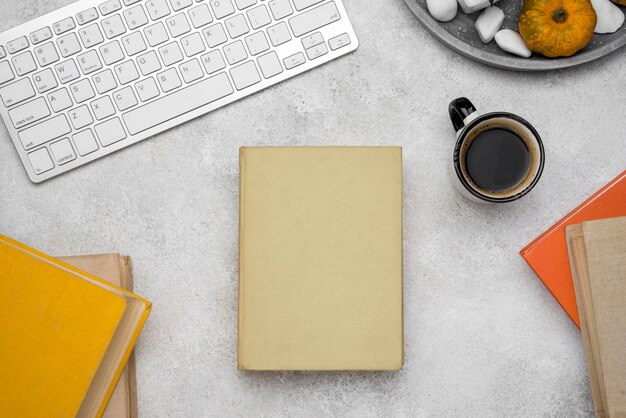 Top view of hardback books on desk with coffee and keyboard