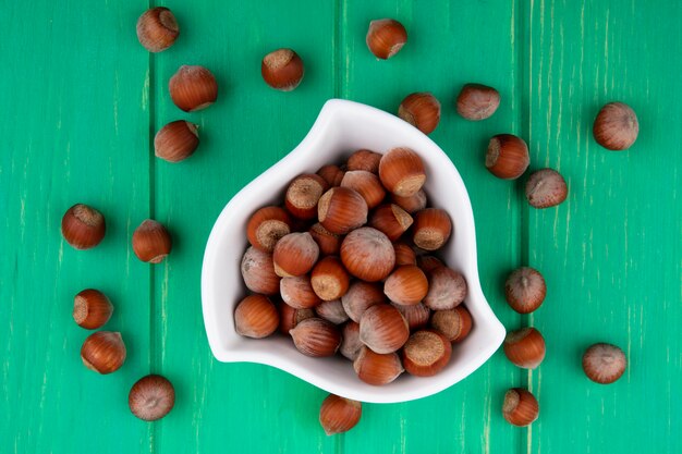 Top view of hazelnut in a bowl on a green surface