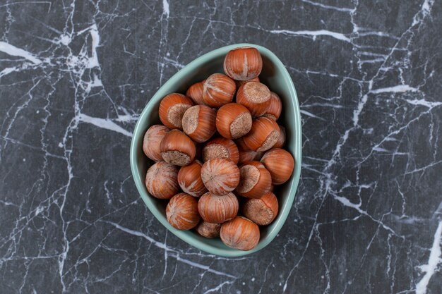 Top view of hazelnuts in blue bowl.