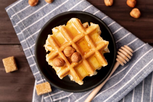 Top view of hazelnuts and honey on top of waffles on plate