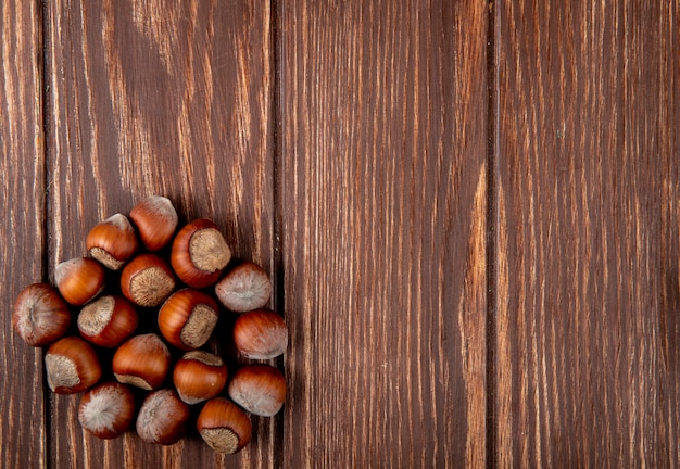 Top view of hazelnuts in shell scattered on wooden background with copy space