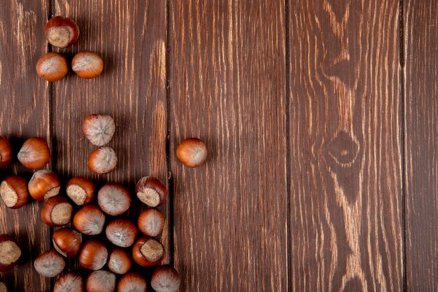 Top view of hazelnuts in shell scattered on wooden background with copy space