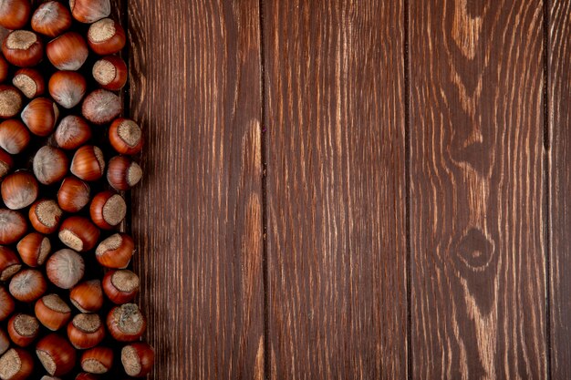 Top view of hazelnuts in shell scattered on wooden background with copy space