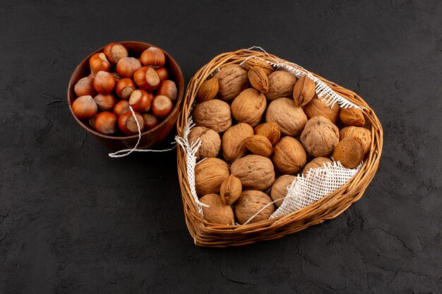 top view hazelnuts and walnuts inside brown pot and basket on the grey