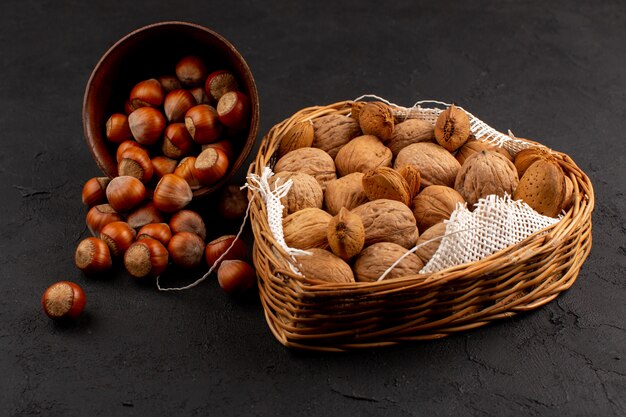 top view hazelnuts and walnuts whole inside pot and basket on the dark floor