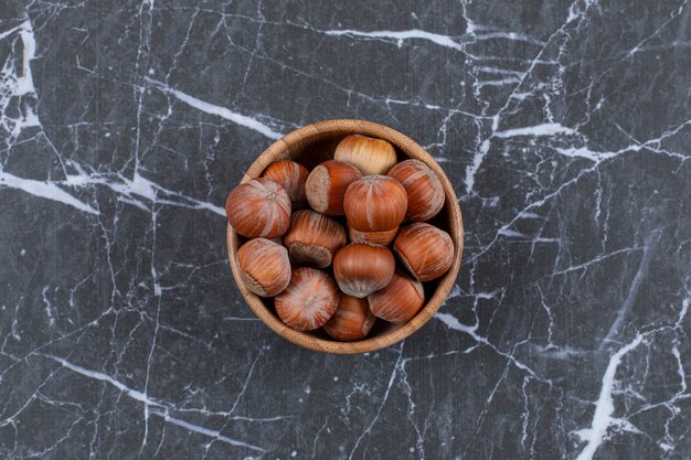 Top view of hazelnuts in wooden bowl.