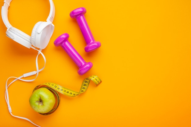 Top view headphones and apple on yellow background