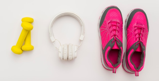 Free photo top view of headphones with sneakers and weights