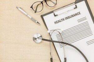 Top view health insurance form and eyeglasses with stethoscope on wooden background.business and healthcare concept.savings.flat lay.copy space.