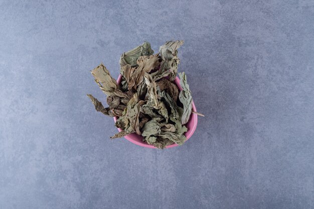 Top view of healthy dry leaves in pink bowl.