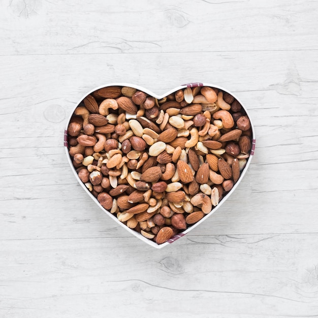 Free photo top view of healthy dryfruits in heart shape on wooden desk