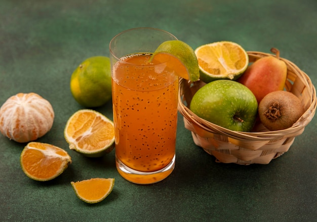 Vista dall'alto di frutta sana e fresca come mele pera kiwi su un secchio con succo di frutta fresca in un bicchiere con mandarini isolati
