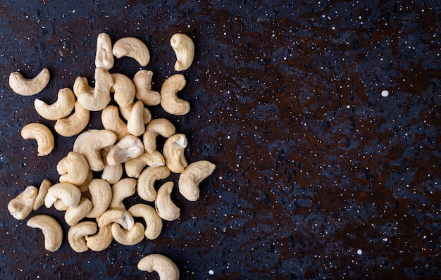 Free photo top view of a heap of cashew nuts on black background with copy s[ace