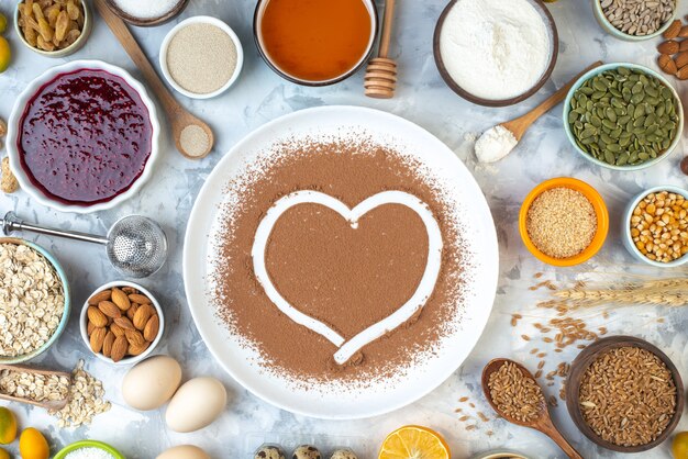 Отпечаток сердца в порошке какао на белых тарелках с другими продуктами на столе, вид сверху