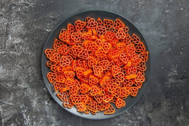 Pasta italiana a forma di cuore vista dall'alto su banda nera su tavolo scuro