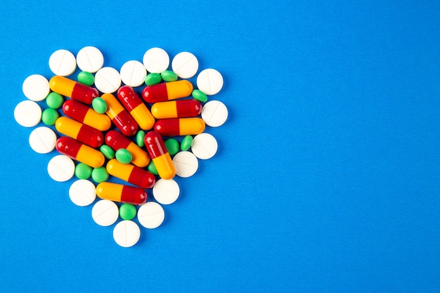 вид сверху таблетки в форме сердца разного цвета на синем фоне