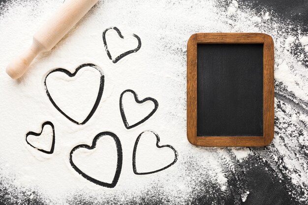 Top view of heart shapes in flour with blackboard