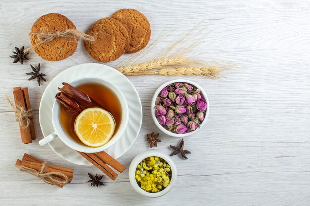 Top view of herbal tea with cinnamon lime lemon and various herbals cookies on white background