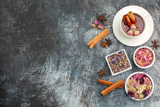 Top view of herbal tea with dry flowers on the left side of grey background