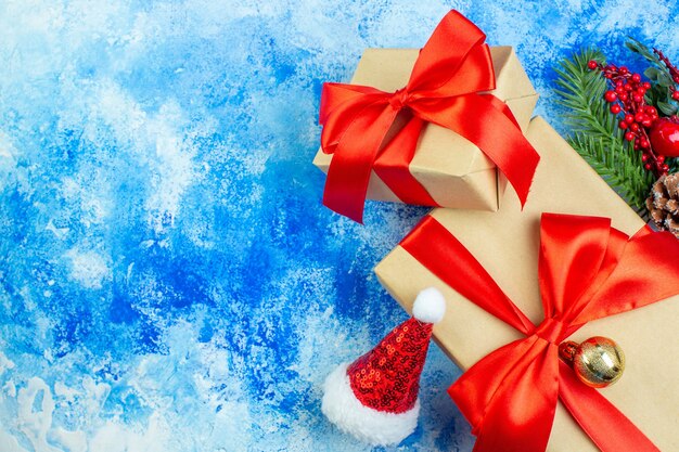 Праздничные подарки, перевязанные красной лентой, рождественские украшения на синем белом столе, свободное место