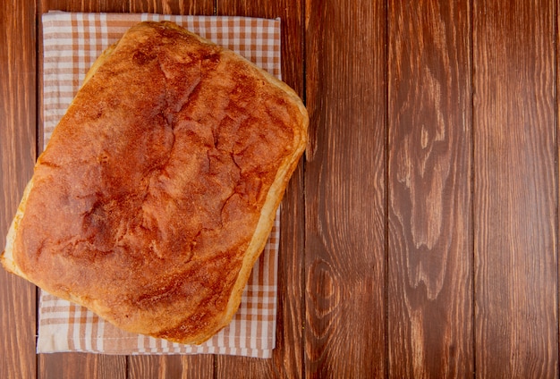 Vista dall'alto di pane fatto in casa sul panno plaid e sullo sfondo in legno con spazio di copia