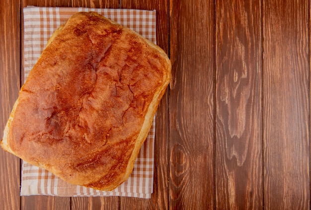 Free photo top view of homemade bread on plaid cloth and wooden background with copy space