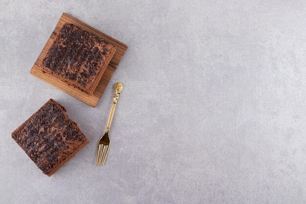 Top view of homemade chocolate on wooden board over grey surface