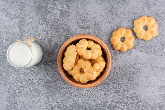 Top view of homemade cookies with milk on grey.