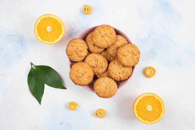 Free photo top view of homemade cookies on wooden board and fresh juicy oranges.