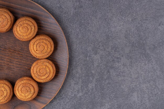 Top view of homemade cookies on wooden plate over grey surface