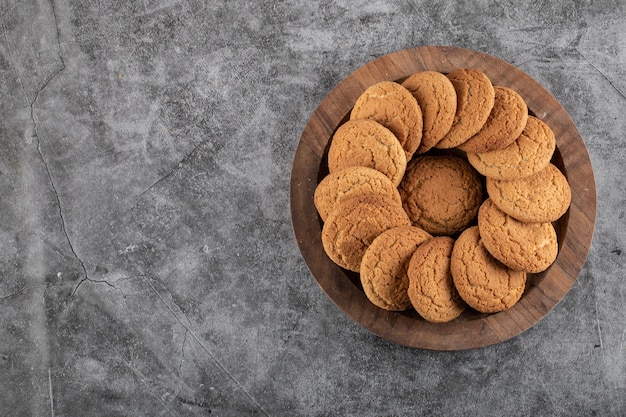 Top view of homemade cookies on wooden tray over grey table. 