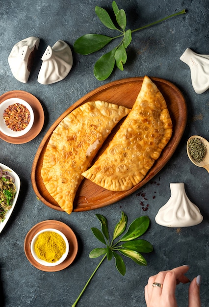 Top view of homemade meat pies belyashi on a wooden platter on dark