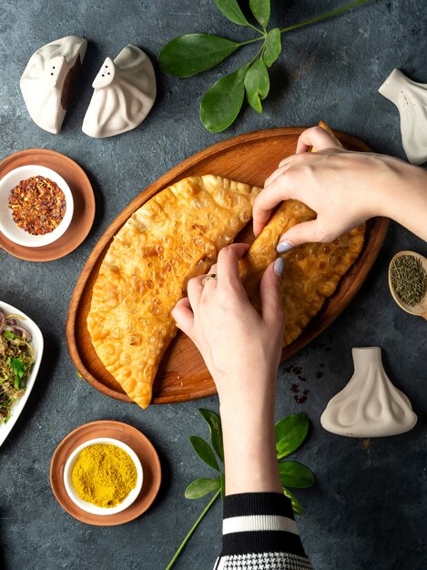 Top view of homemade meat pies belyashi on a wooden platter on dark